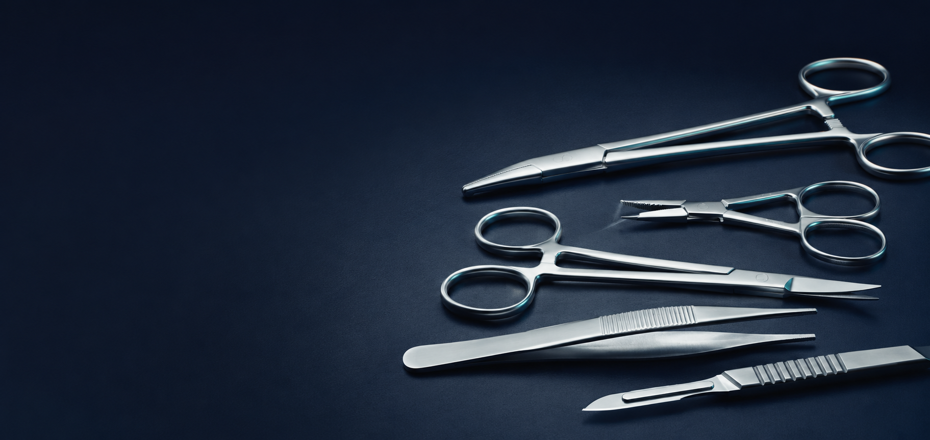Precision stainless-steel surgical instruments arranged on a navy surface